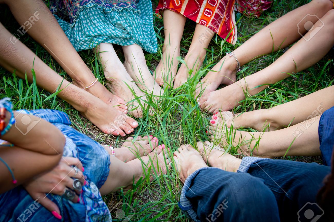 bare feet of group of young girls in a circle on a green grass stock