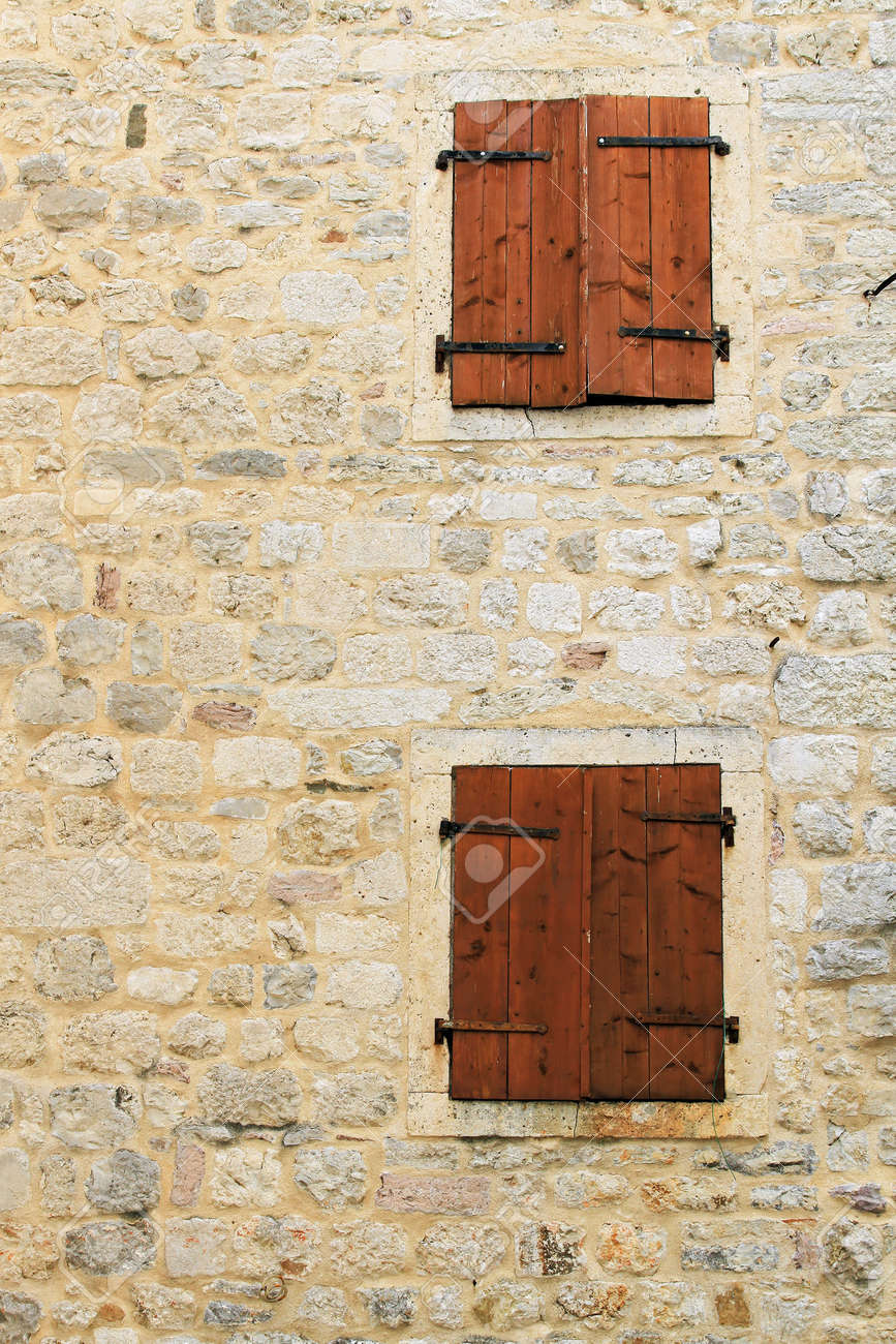 Stock photo two closed windows with blinds at old stone house
