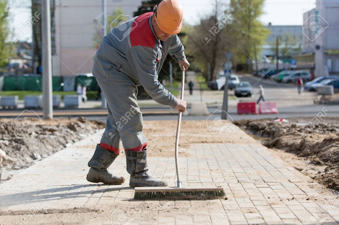 Construction Worker Grouting Dry Sand With Brush Into Paver Bricks Joints  During Road Works Stock Photo, Picture and Royalty Free Image. Image  55641666.