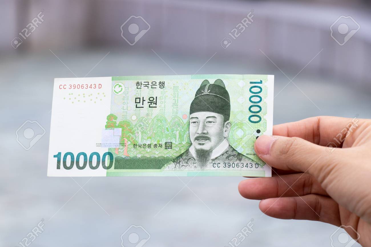 Man Hold South Korea Banknote 10000 Won On Blurred Background Stock Photo,  Picture and Royalty Free Image. Image 117312579.