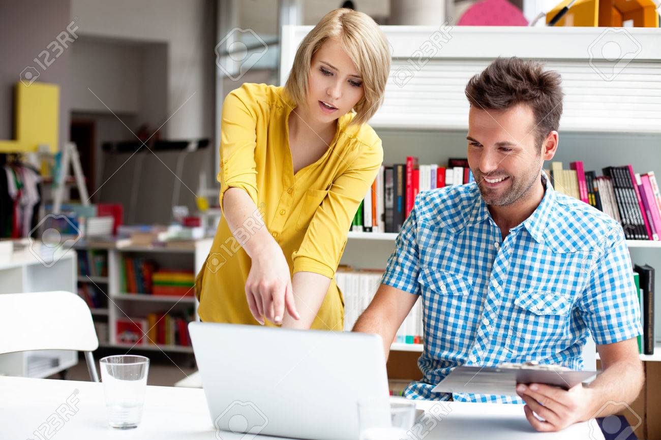 Two bookshop managers working on laptop. - 53952155 Two bookshop managers working on laptop. - 53952155