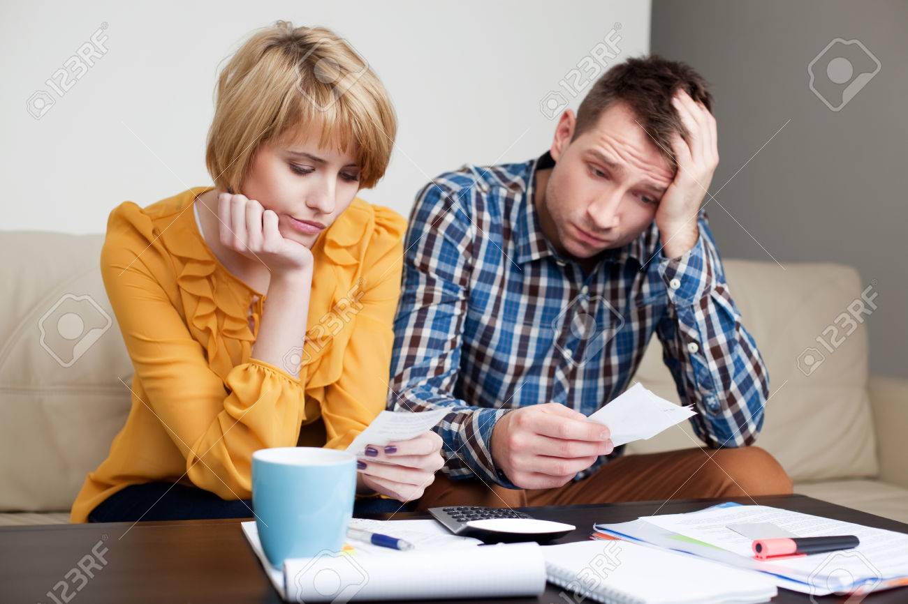 Sad, depressed young couple paying bills. - 53953443 Sad, depressed young couple paying bills. - 53953443