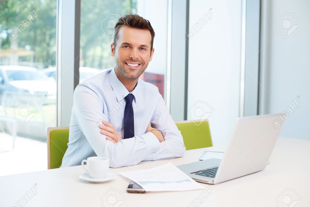 53957368-happy-man-sitting-at-desk-in-the-office.jpg