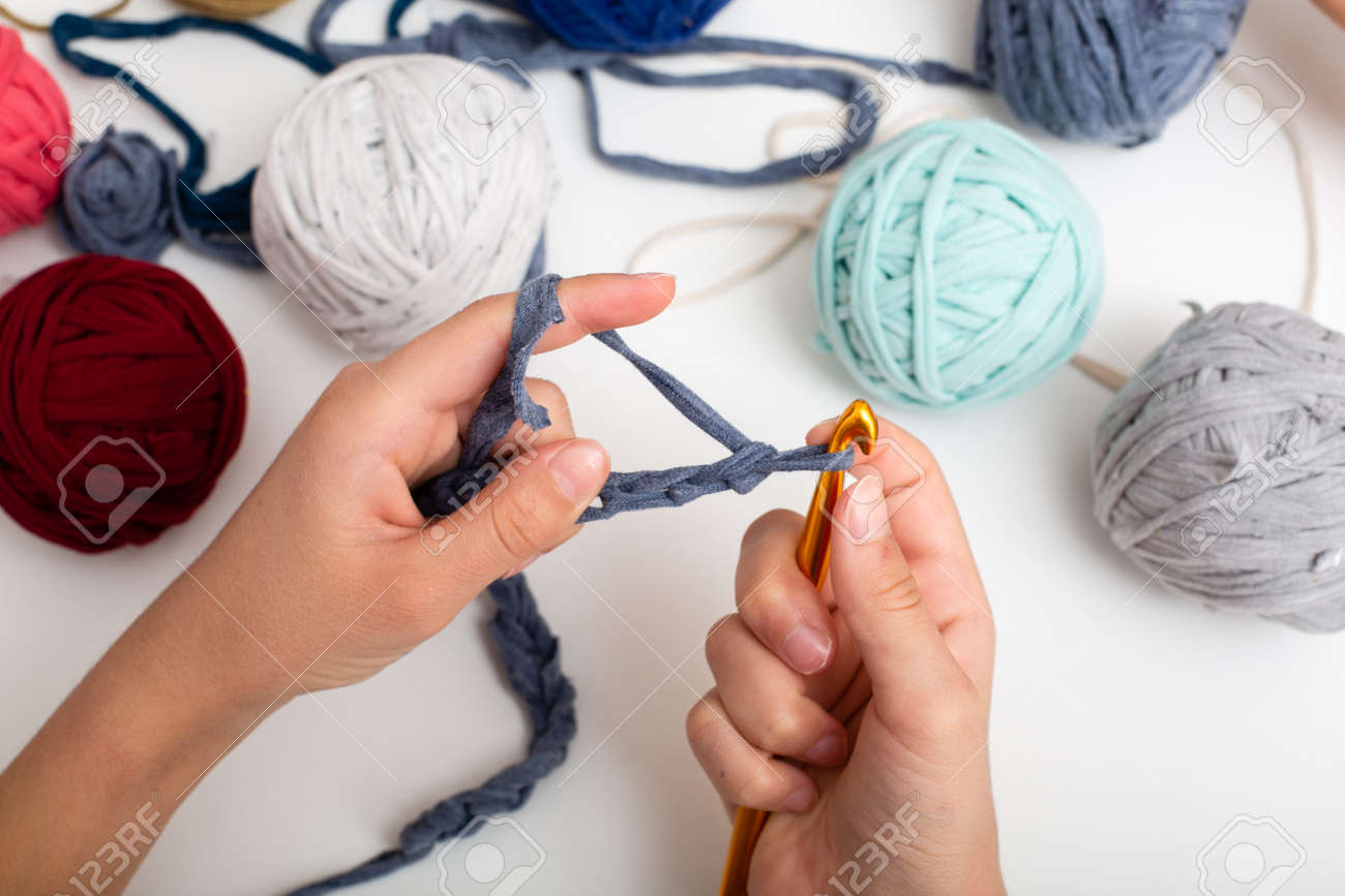 Different colored balls of yarn. Children's hands are crocheted and thread view frome above on white table - 167297659 Different colored balls of yarn. Children's hands are crocheted and thread view frome above on white table - 167297659
