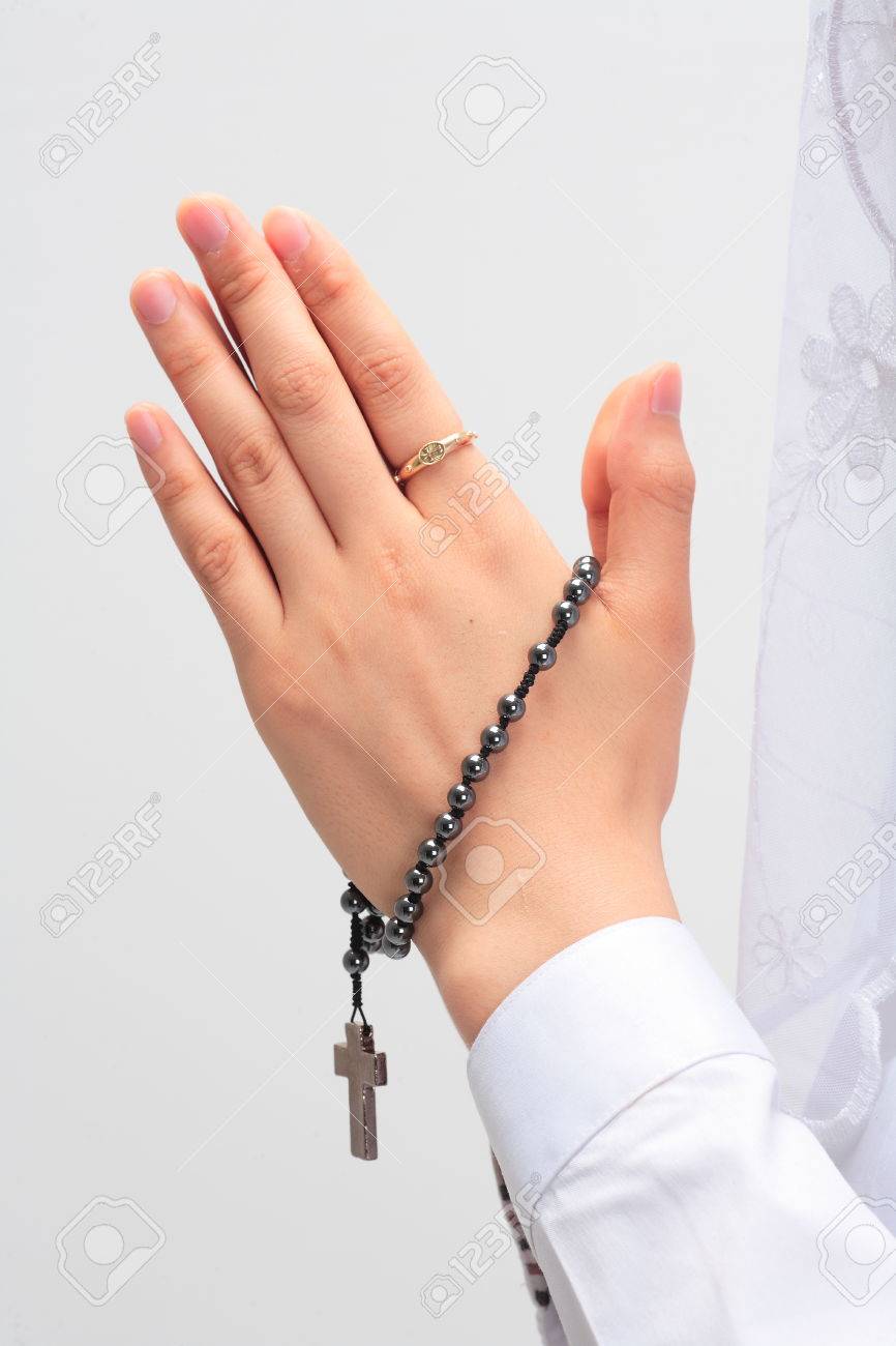 isolated shot of praying hands with a rosary in hands of a female