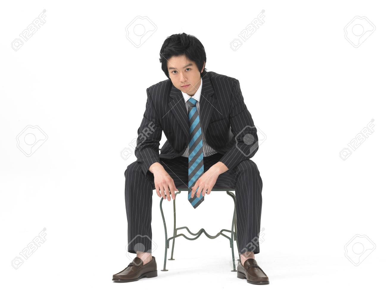 アジアの男モデルの正式なビジネスは 椅子に座っているようなスタジオでのポーズファッション の写真素材 画像素材 Image