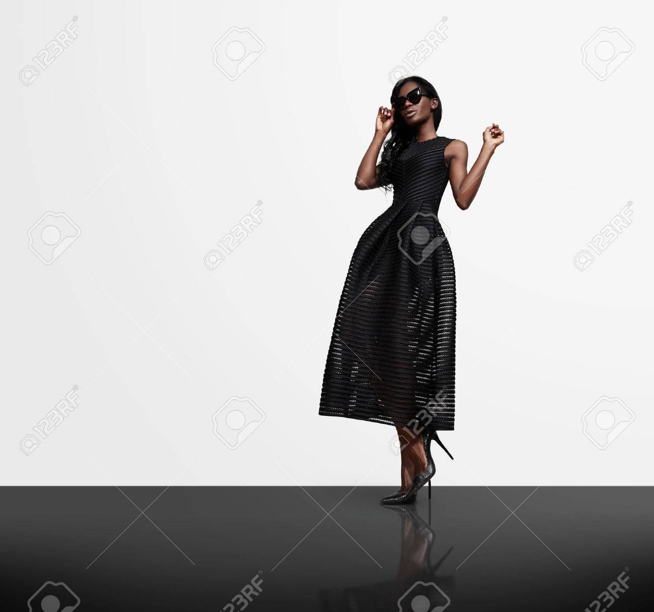 woman wearing black dress on a white wall background and black cristal flor - 42417396 woman wearing black dress on a white wall background and black cristal flor - 42417396