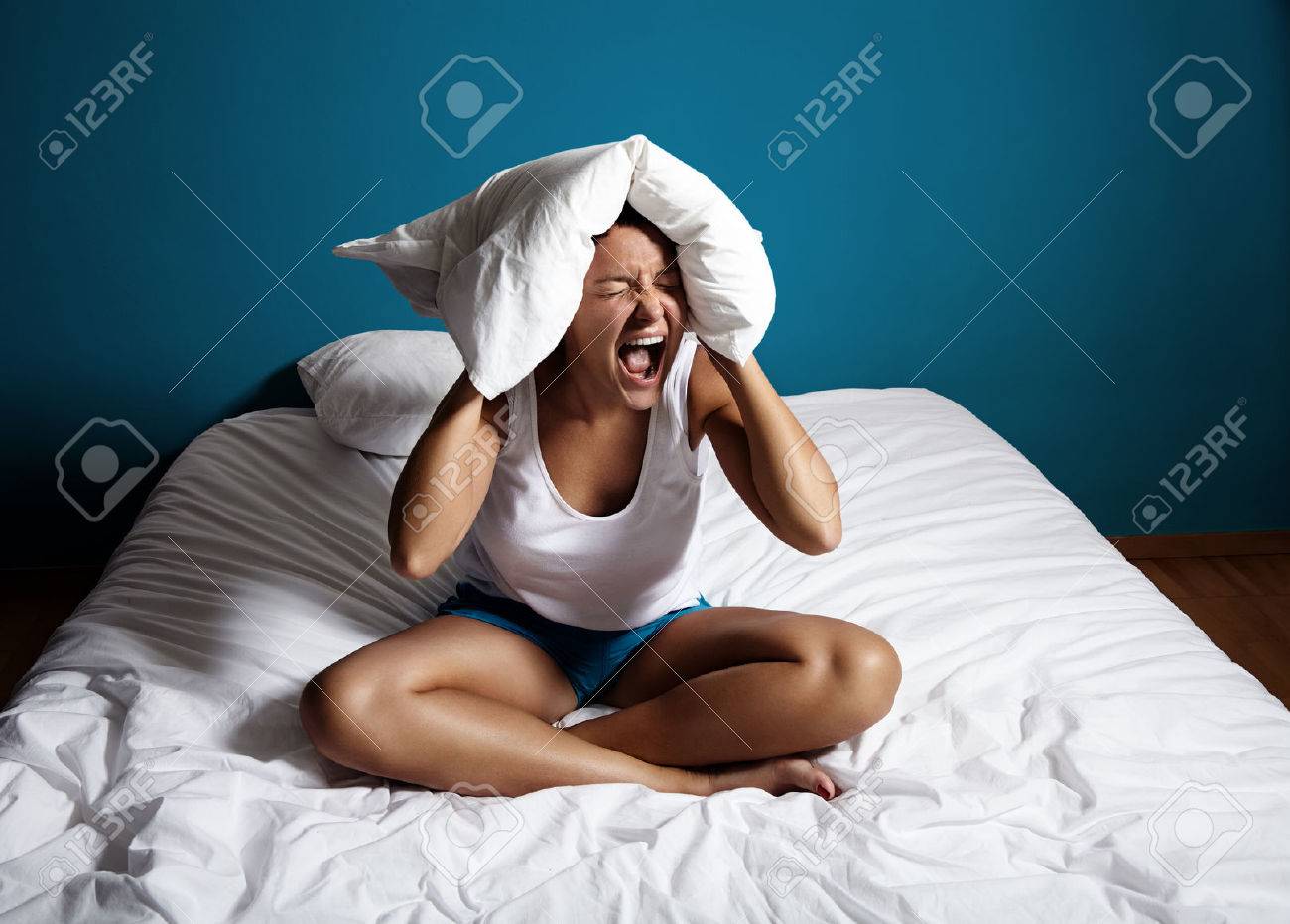 woman siiting on a bed and screamin, close her ears with a pillow - 43153961 woman siiting on a bed and screamin, close her ears with a pillow - 43153961