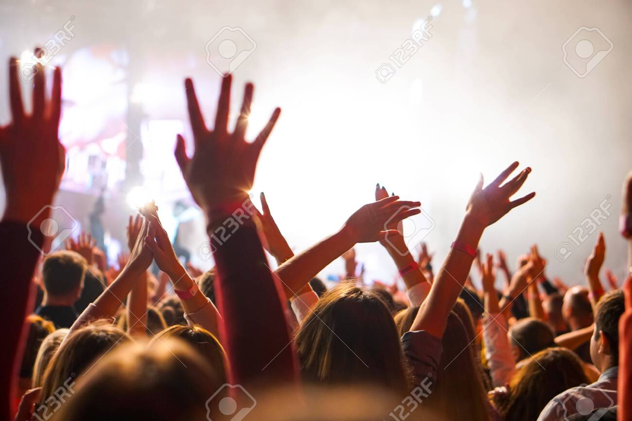 Crowd at a music concert, audience raising hands up - 138765424 Crowd at a music concert, audience raising hands up - 138765424