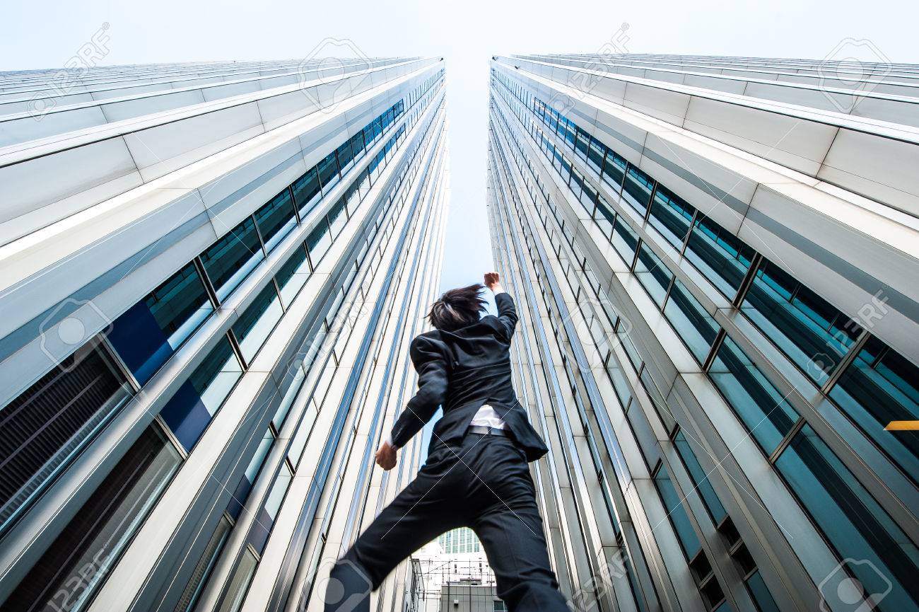 businessman jumping over the camera low angle building background