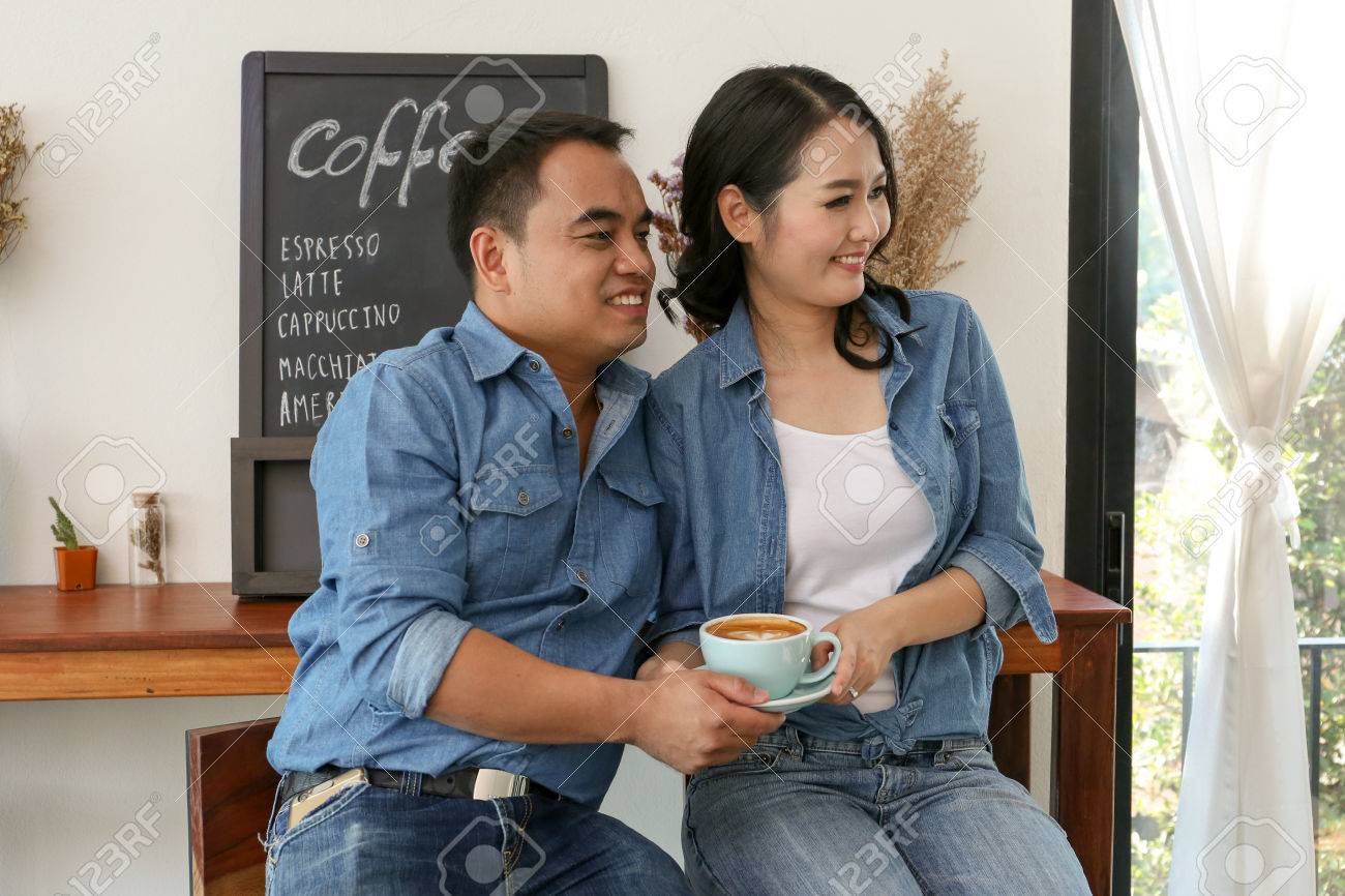幸せなアジア カップル喫茶店でコーヒー カップを保持します の写真素材 画像素材 Image