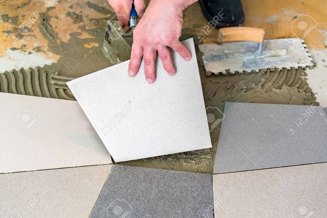 Handyman Laying Ceramic Floor Tiles On Adhesive Using Trowel Stock