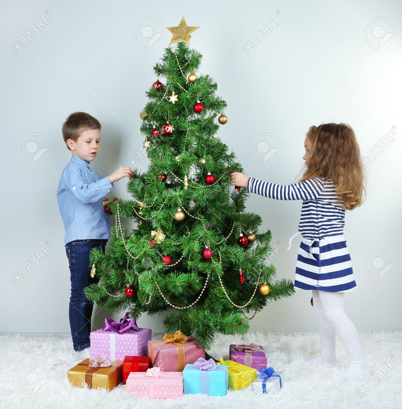 Kids Decorating For Christmas kids decorating christmas tree with baubles in room stock photo Kids Decorating For Christmas kids decorating christmas tree with baubles in room stock photo