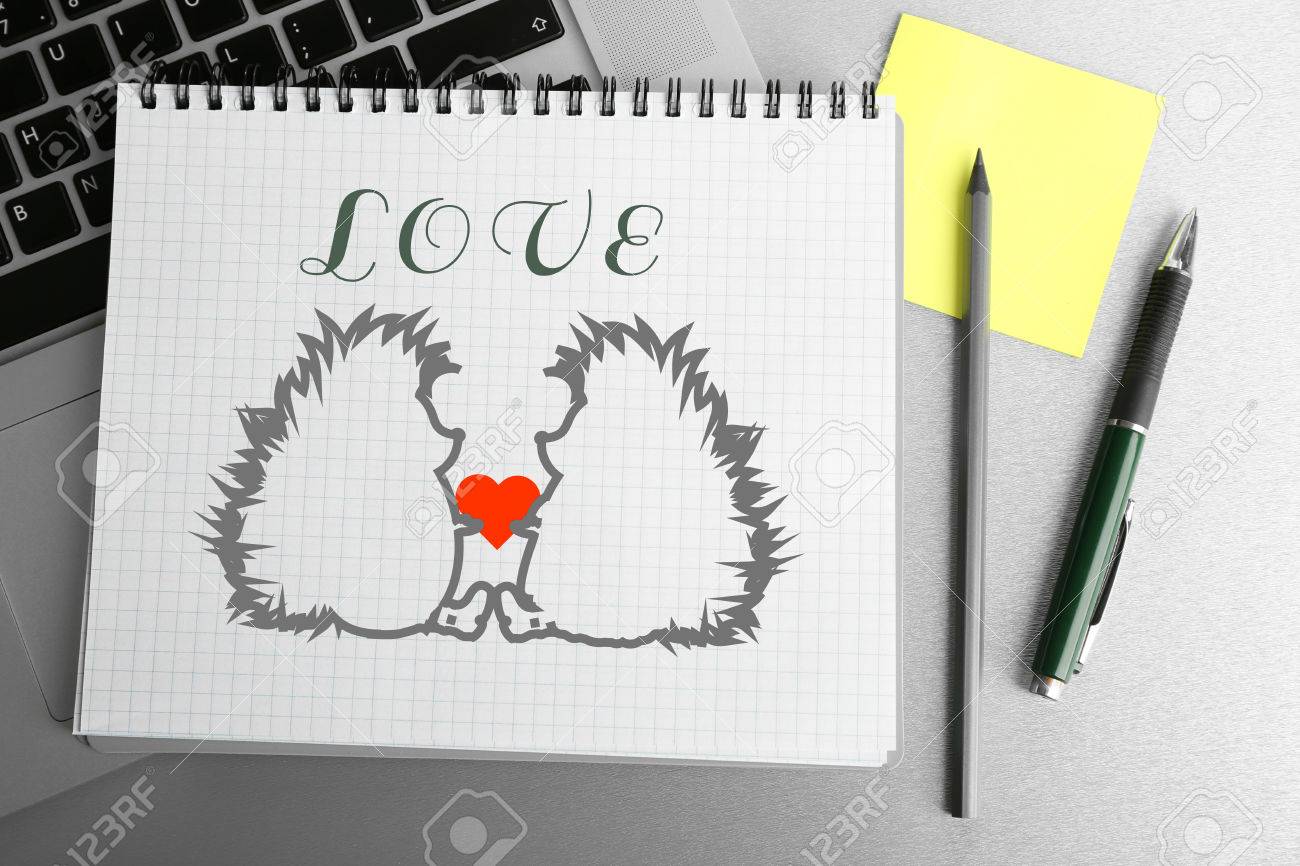 notebook with drawings on laptop keyboard pen and coffee cup
