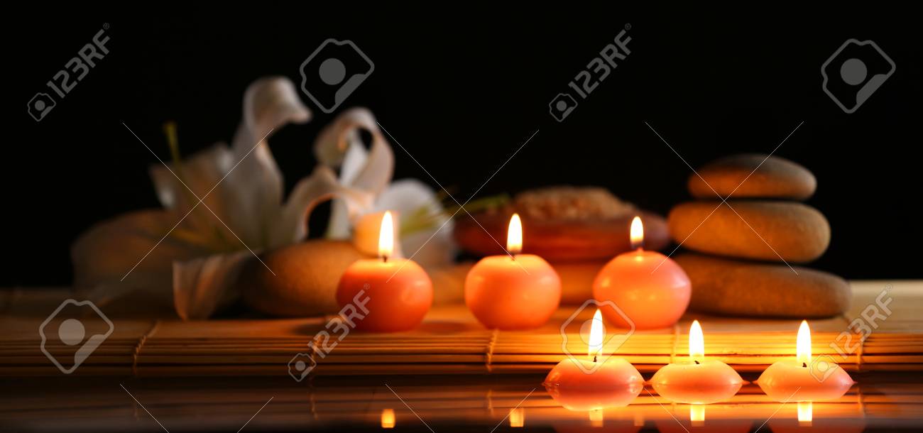 spa still life with stones candles and flowers in water on black