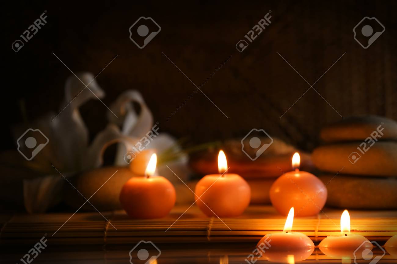 spa still life with stones candles and flowers in water on dark