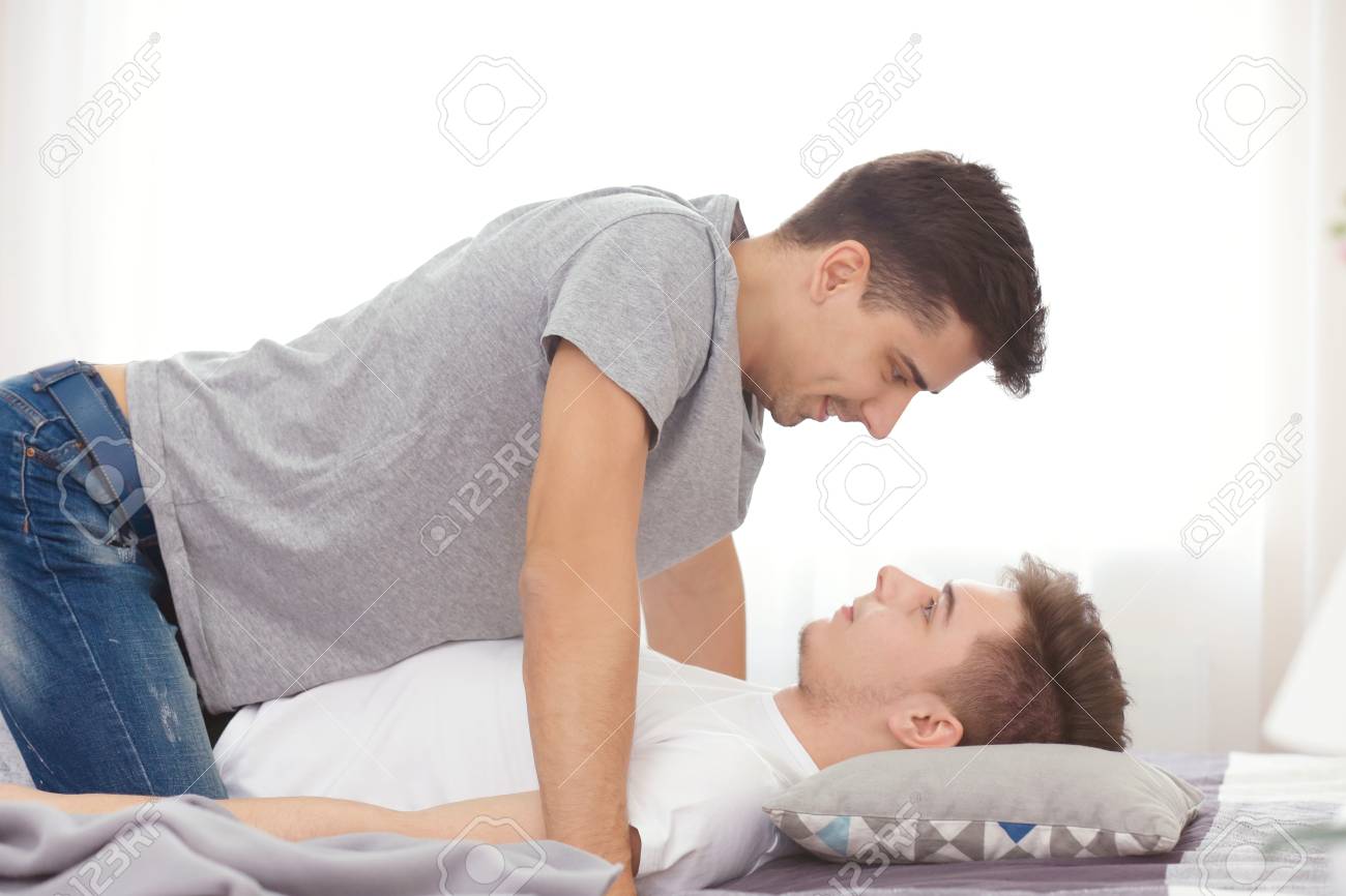 自宅でベッドの上で一緒に幸せなゲイのカップル の写真素材 画像素材 Image