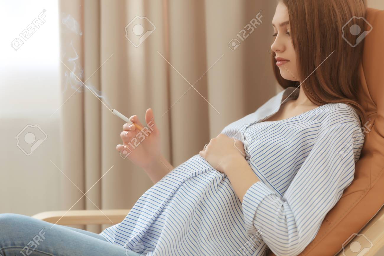 自宅の椅子に座ってタバコを吸う妊婦 の写真素材 画像素材 Image
