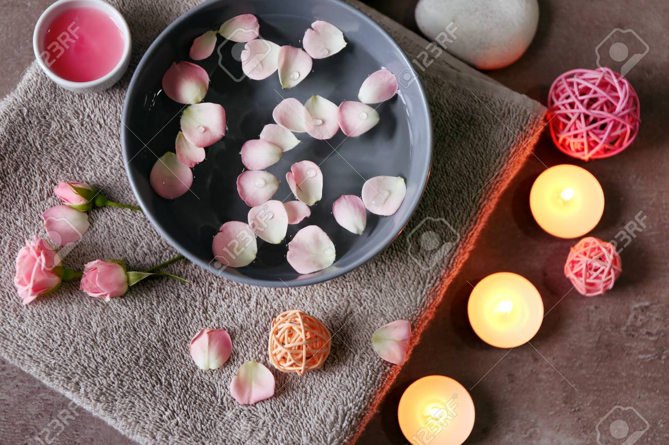 Beautiful spa composition of flower petals with water in bowl and candles on gray background - 97642824 Beautiful spa composition of flower petals with water in bowl and candles on gray background - 97642824