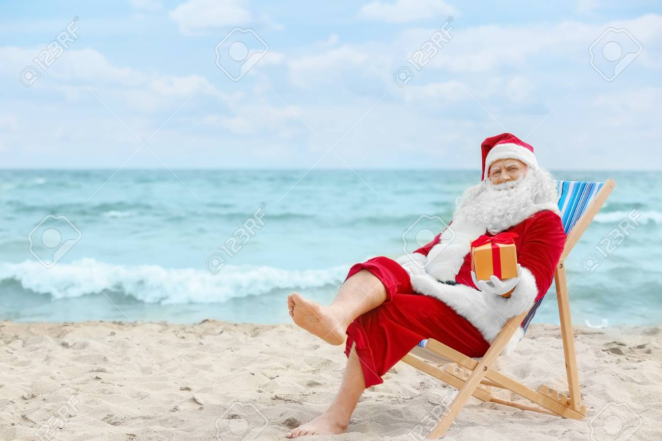 Authentic Santa Claus With Gift Box In Deck Chair On Beach Stock Photo Picture And Royalty Free Image Image 98713664