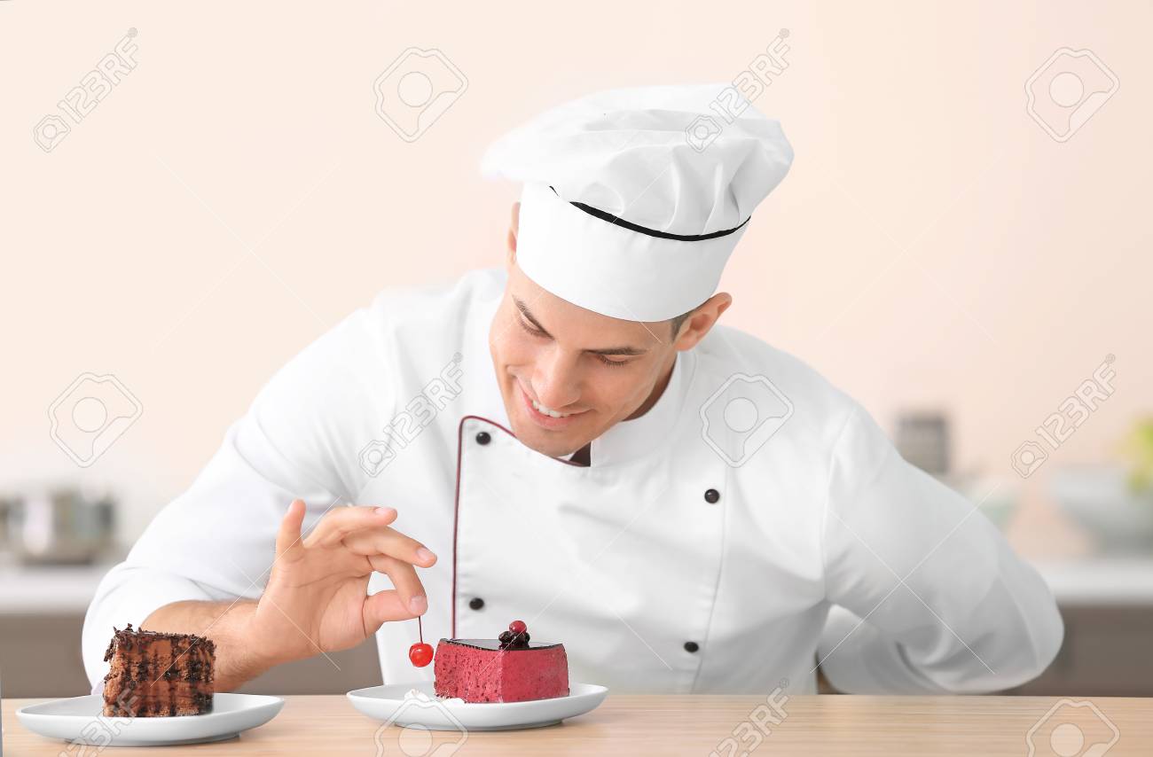 Young Male Chef Decorating Tasty Dessert In Kitchen Stock Photo