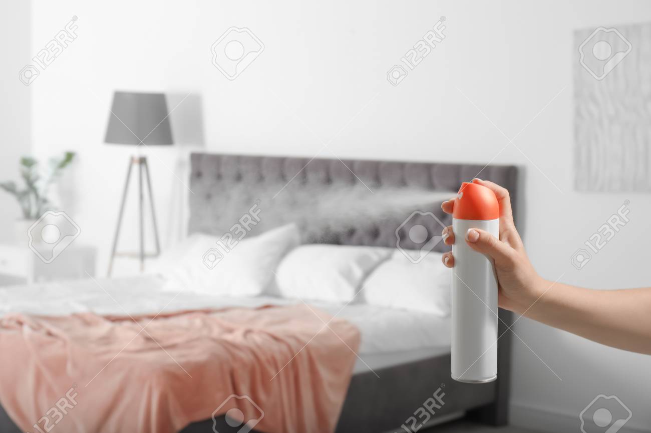 Woman Spraying Air Freshener In Bedroom 