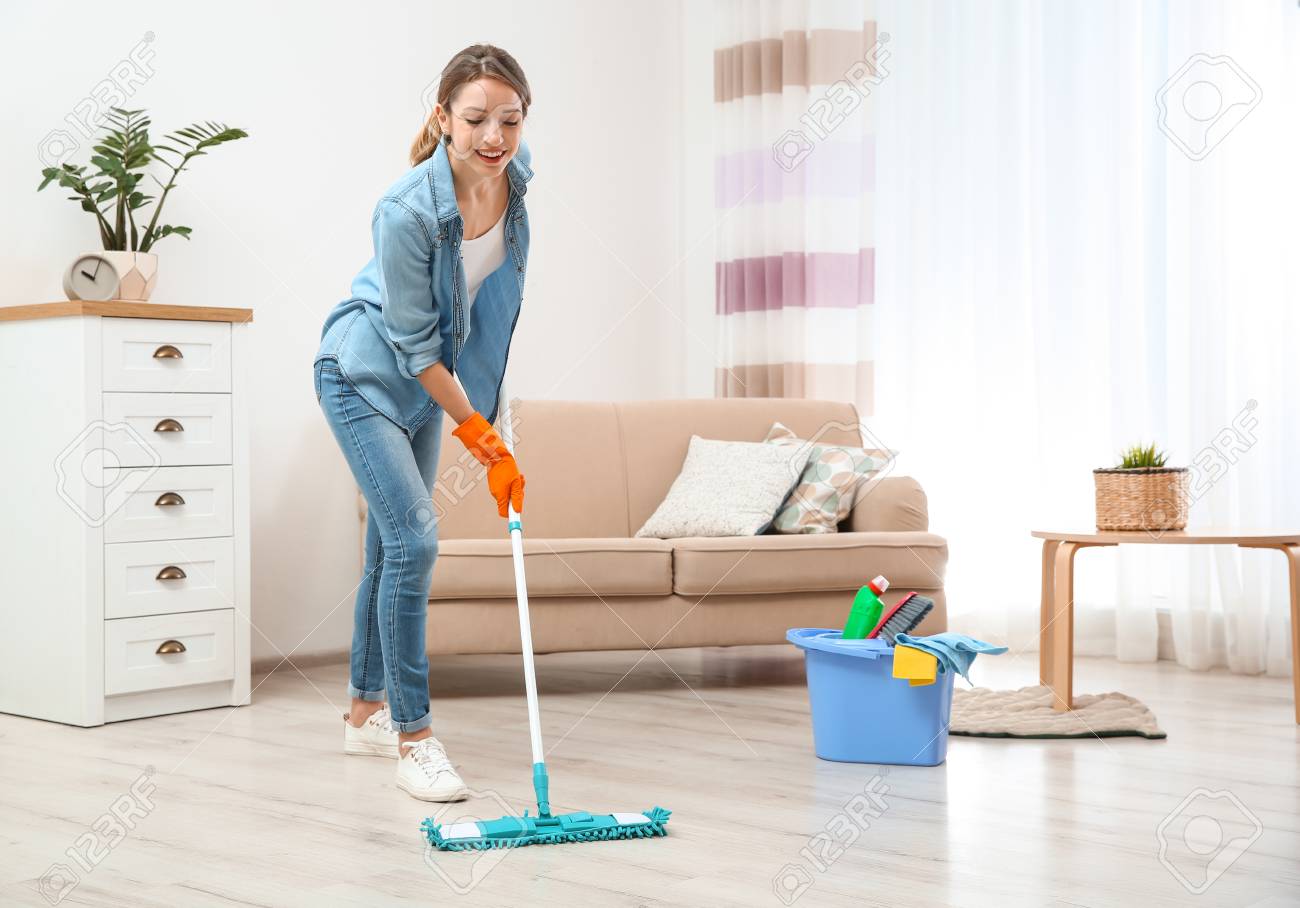 Young woman washing floor with mop in living room. Cleaning service - 114816414 Young woman washing floor with mop in living room. Cleaning service - 114816414