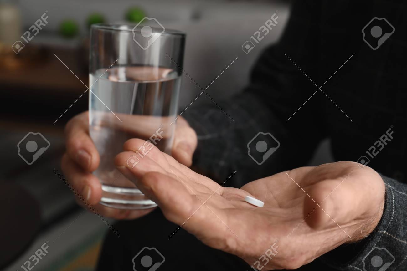 Senior man holding pill and glass of water indoors, closeup - 114652261 Senior man holding pill and glass of water indoors, closeup - 114652261