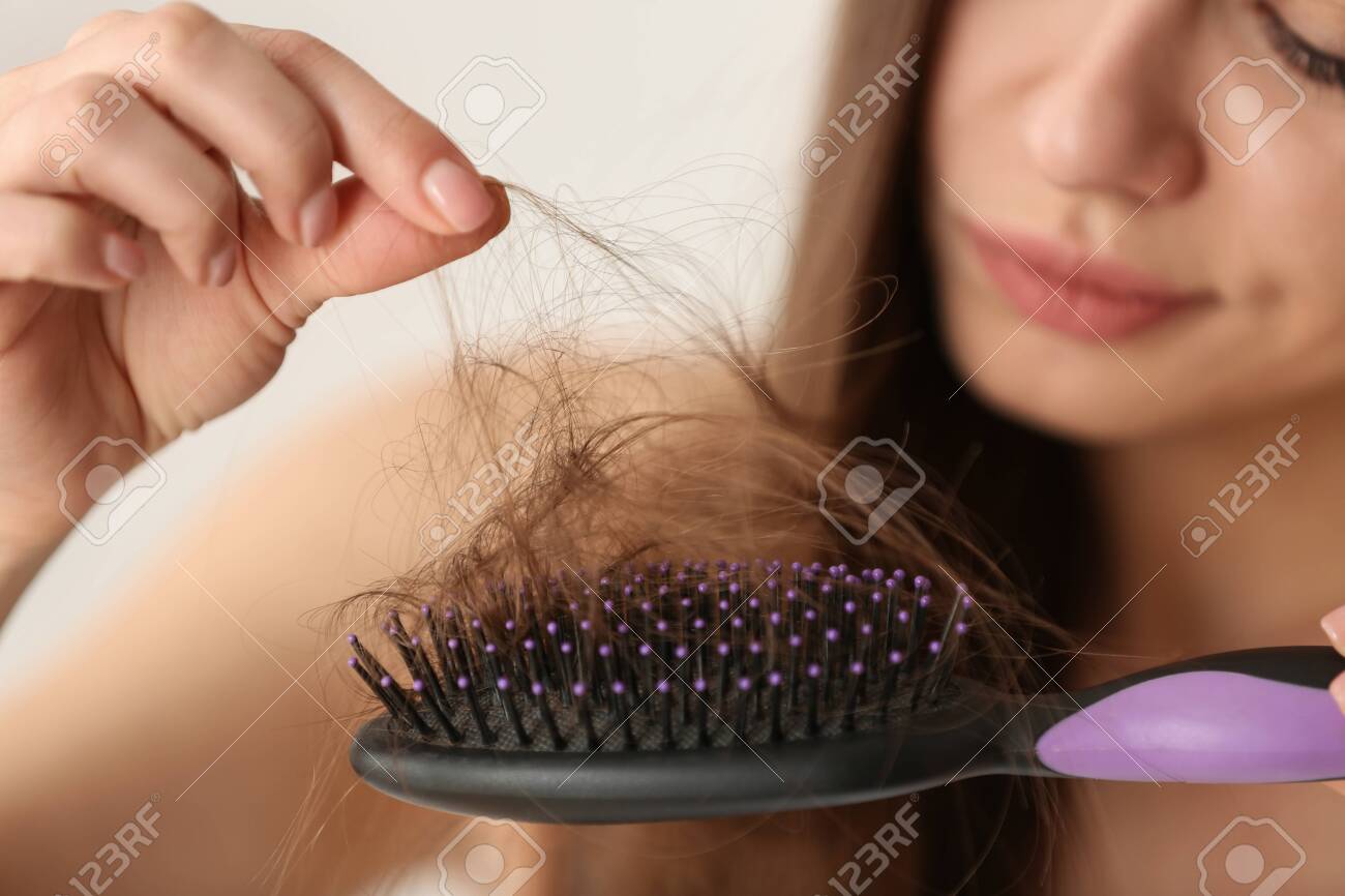 Woman untangling her hair from brush on light background, closeup - 120331680 Woman untangling her hair from brush on light background, closeup - 120331680