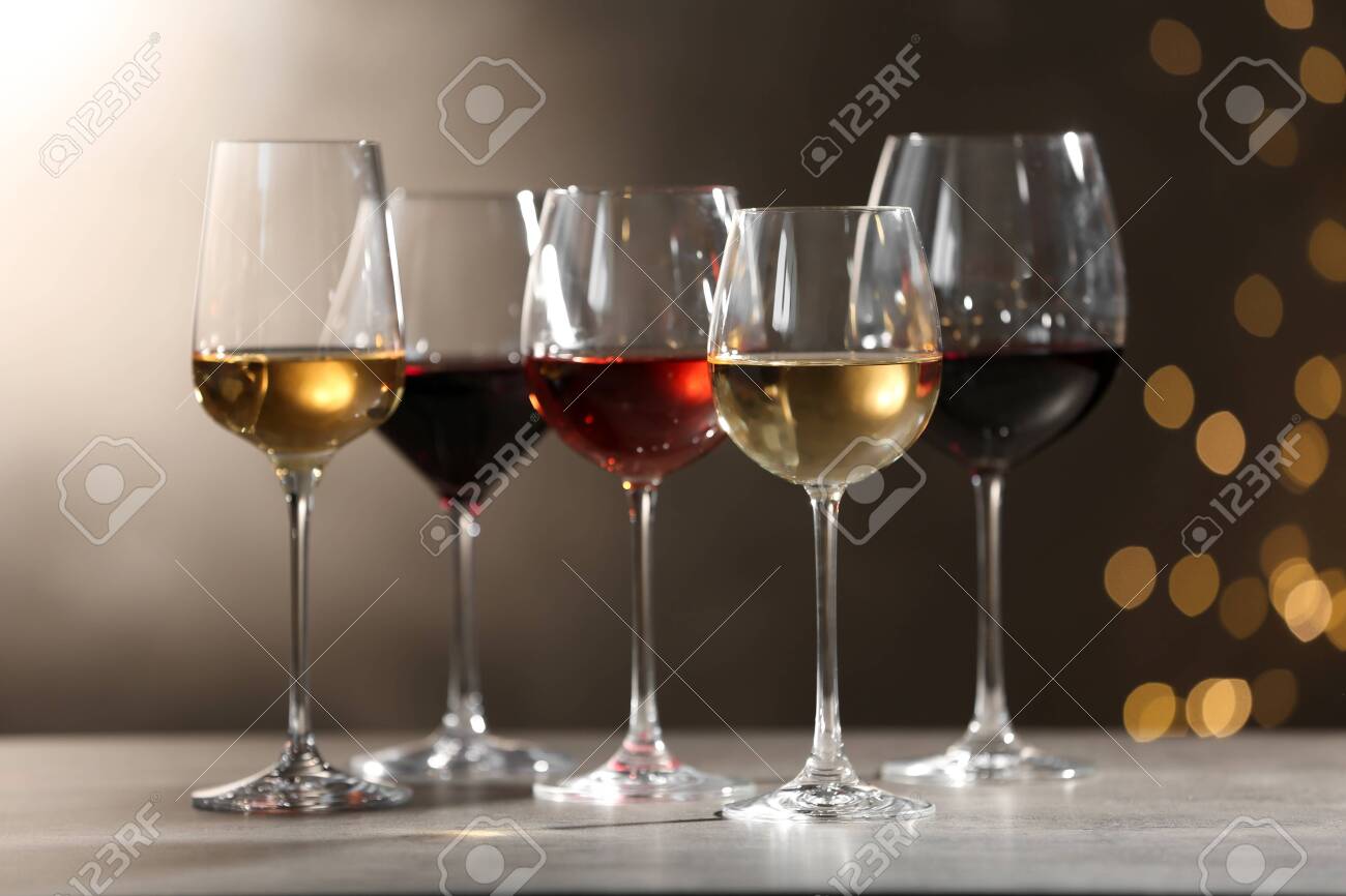 Glasses with different wines on grey table against defocused lights - 122529398 Glasses with different wines on grey table against defocused lights - 122529398