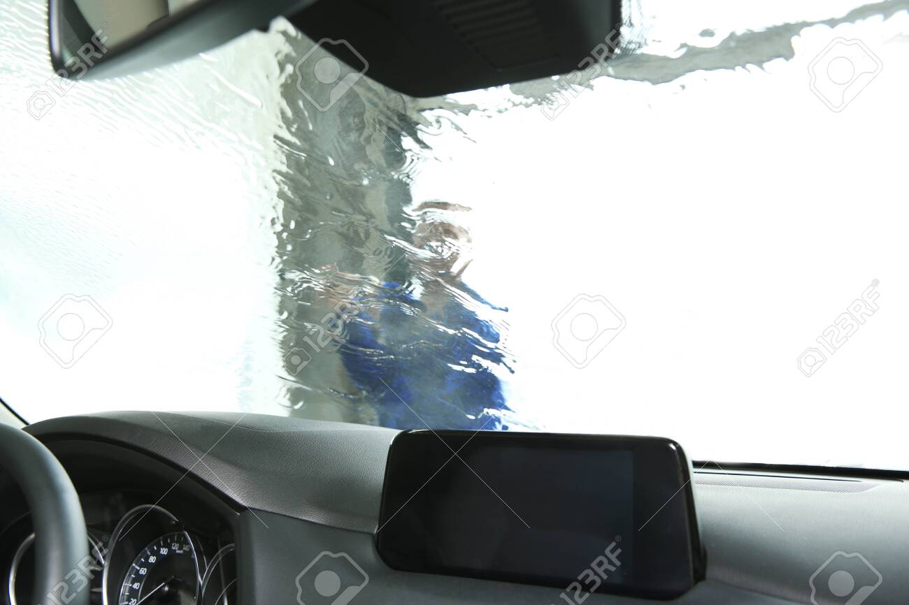 Worker Cleaning Automobile Windshield With High Pressure Water