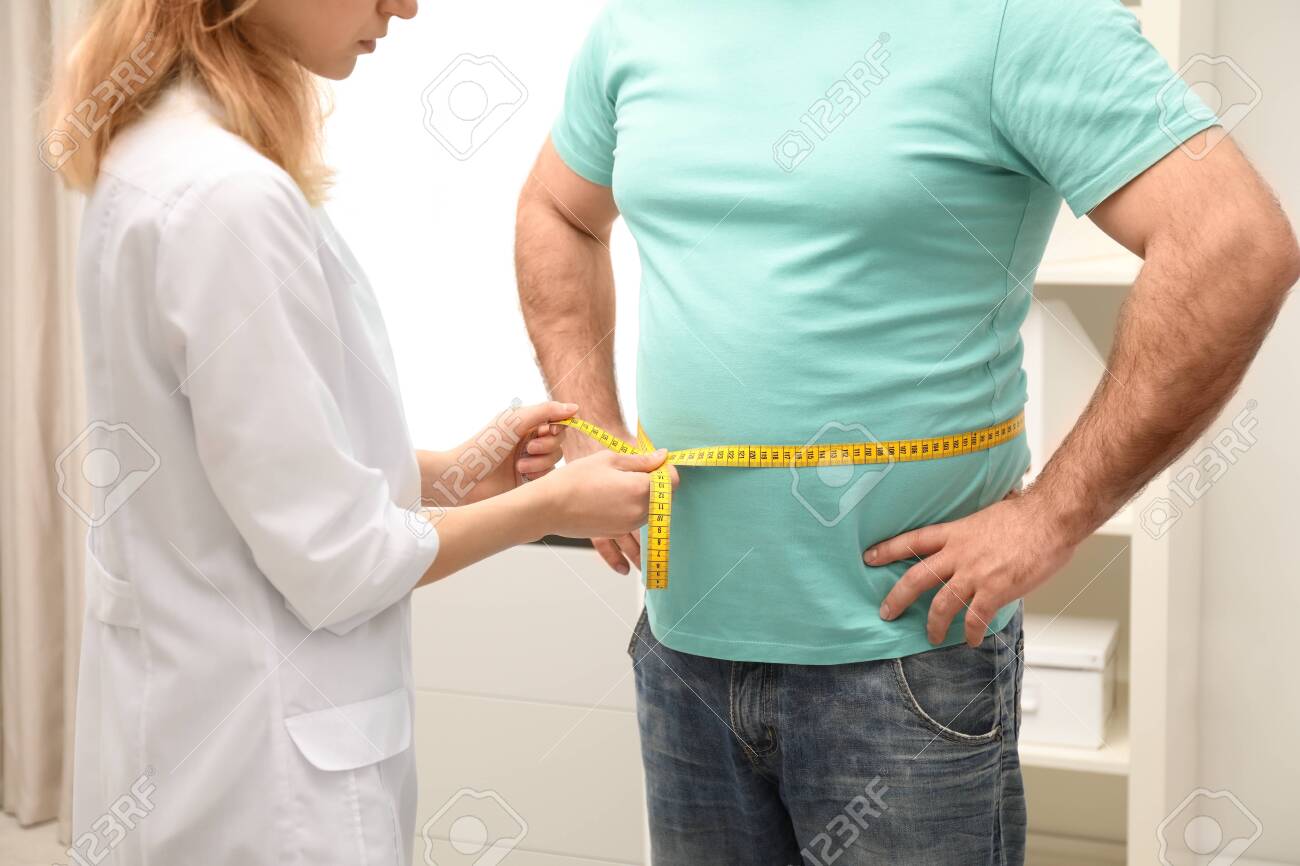 Doctor measuring overweight man's waist in hospital, closeup - 123202756 Doctor measuring overweight man's waist in hospital, closeup - 123202756