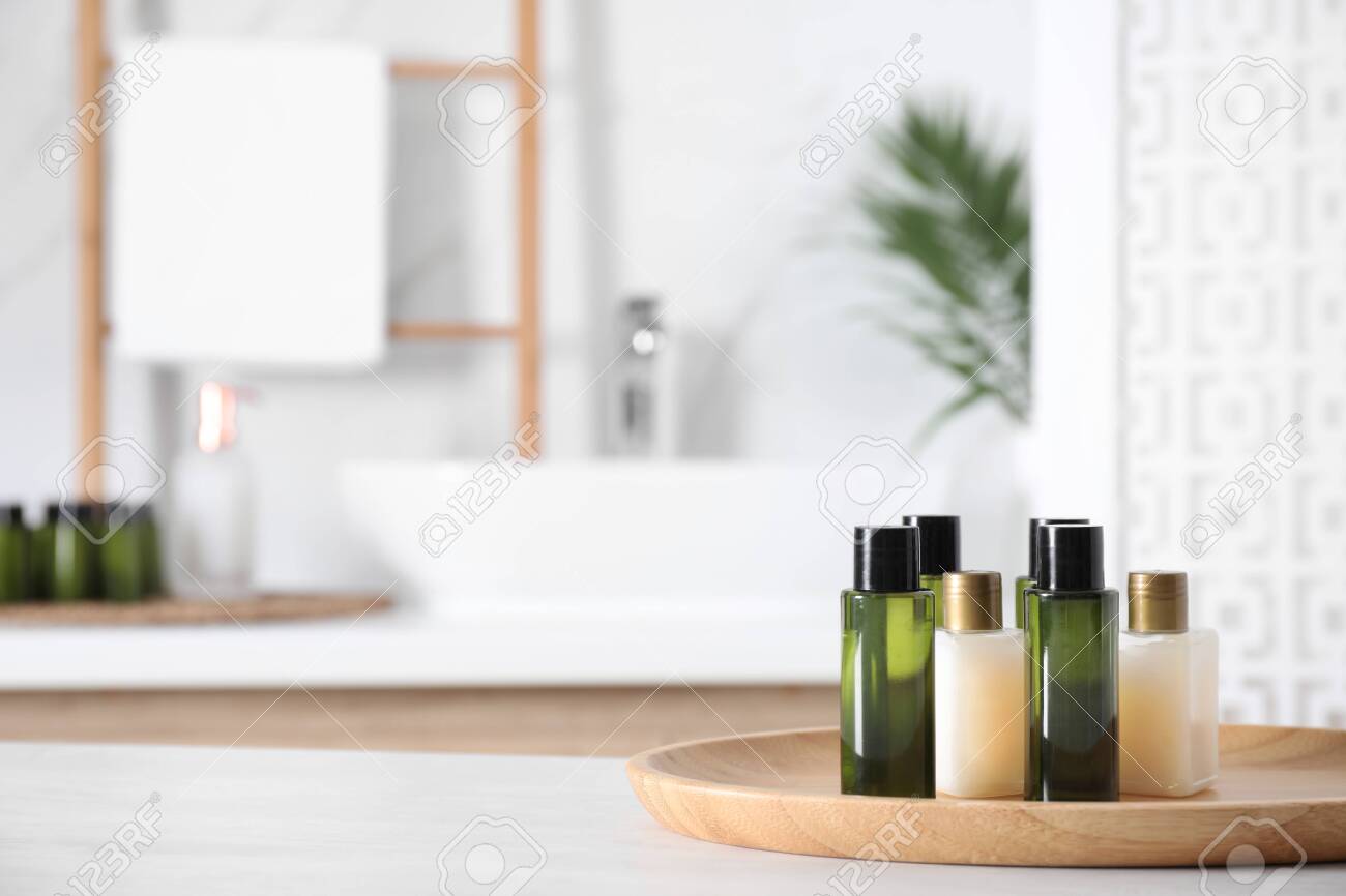 Wooden tray with mini bottles of cosmetic products on white table in bathroom. Space for text - 131683973 Wooden tray with mini bottles of cosmetic products on white table in bathroom. Space for text - 131683973
