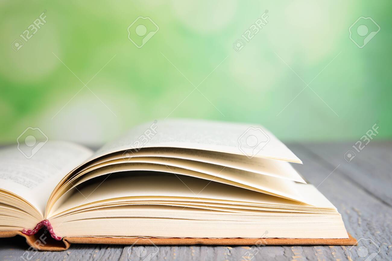 Open book on grey wooden table against blurred green background, closeup. Space for text - 131818687 Open book on grey wooden table against blurred green background, closeup. Space for text - 131818687