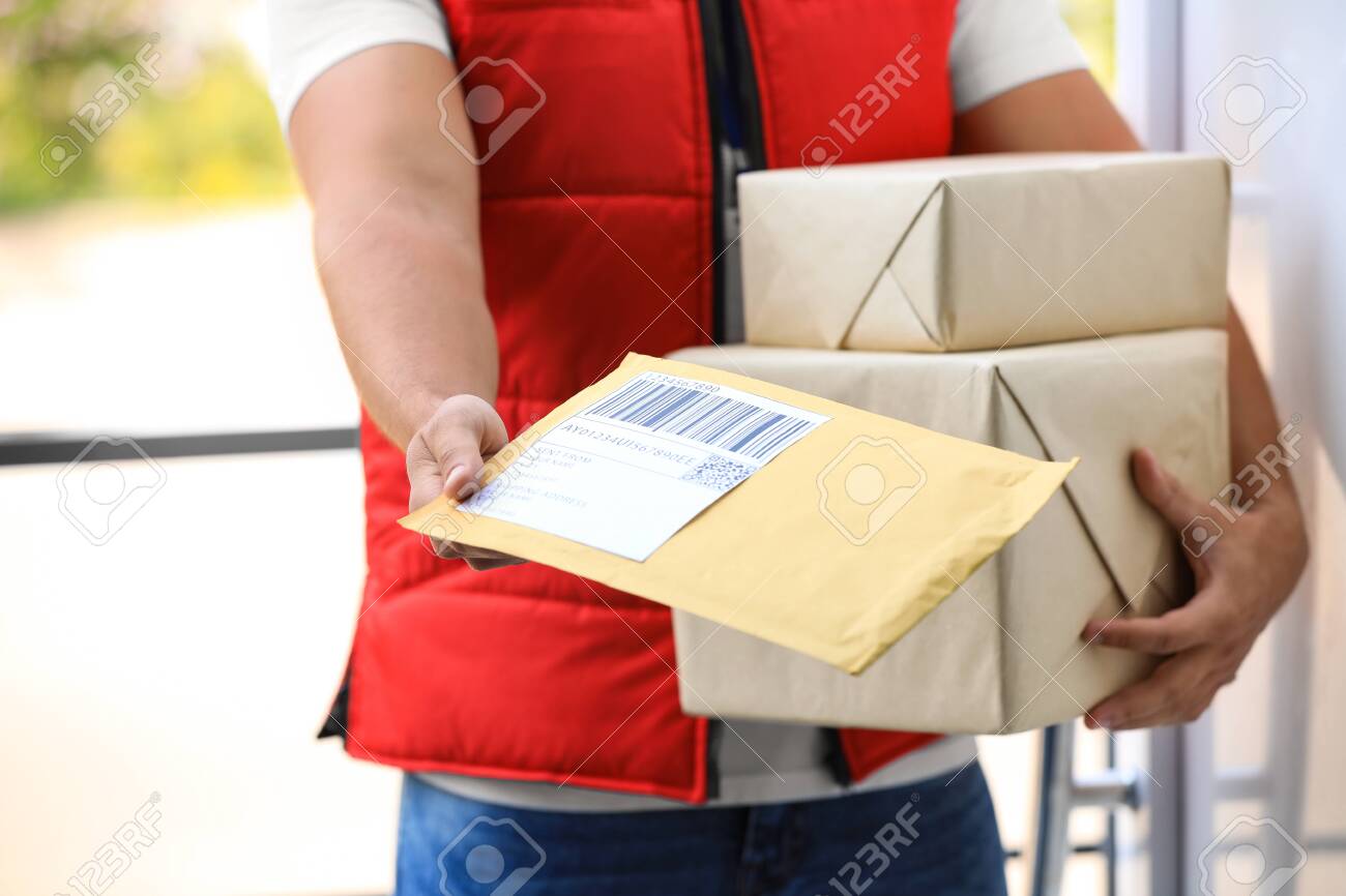 Young courier holding parcels on doorstep, closeup. Delivery service - 132290443 Young courier holding parcels on doorstep, closeup. Delivery service - 132290443