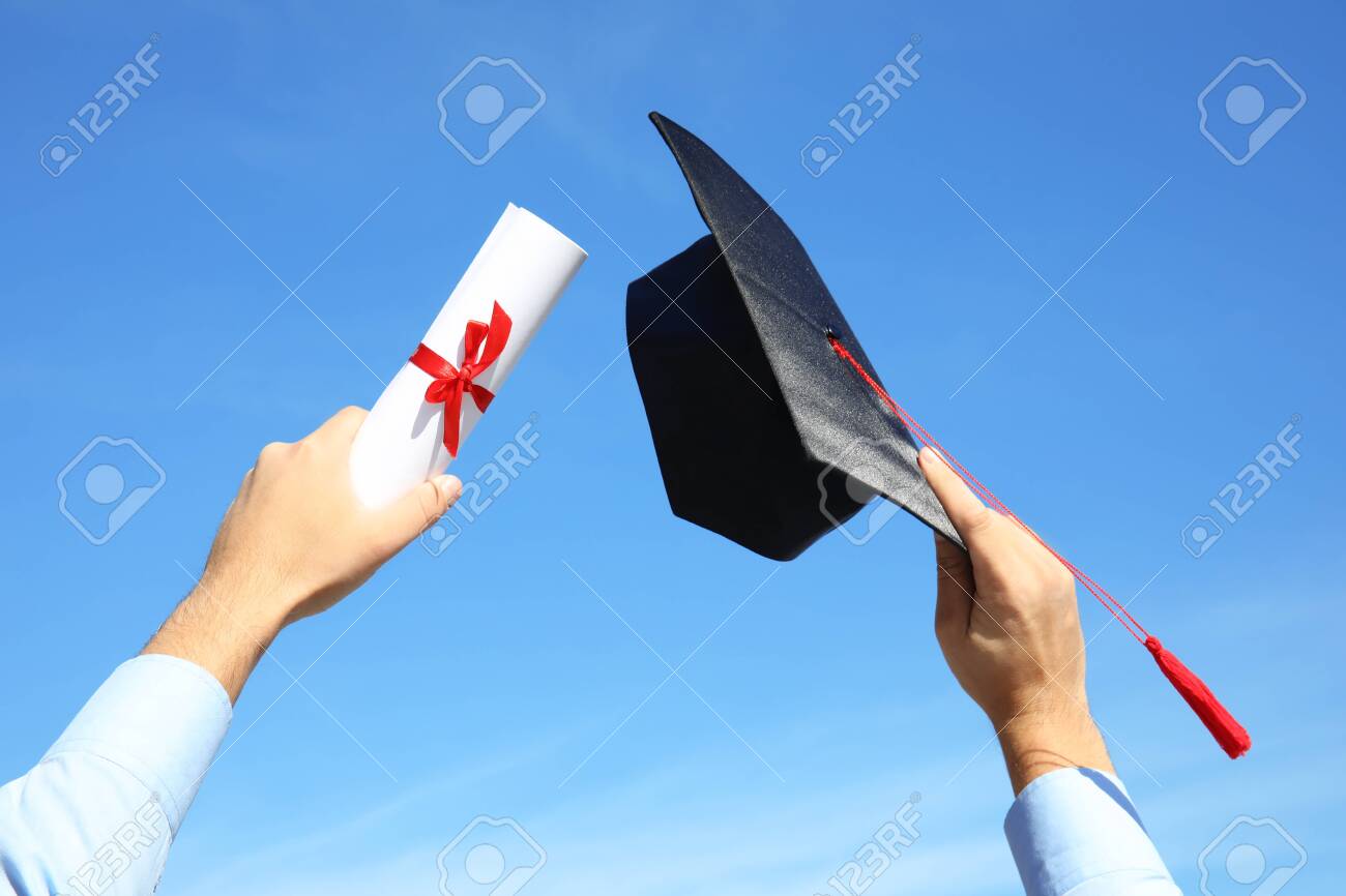 Student with graduation hat and diploma against blue sky, closeup - 132634266 Student with graduation hat and diploma against blue sky, closeup - 132634266