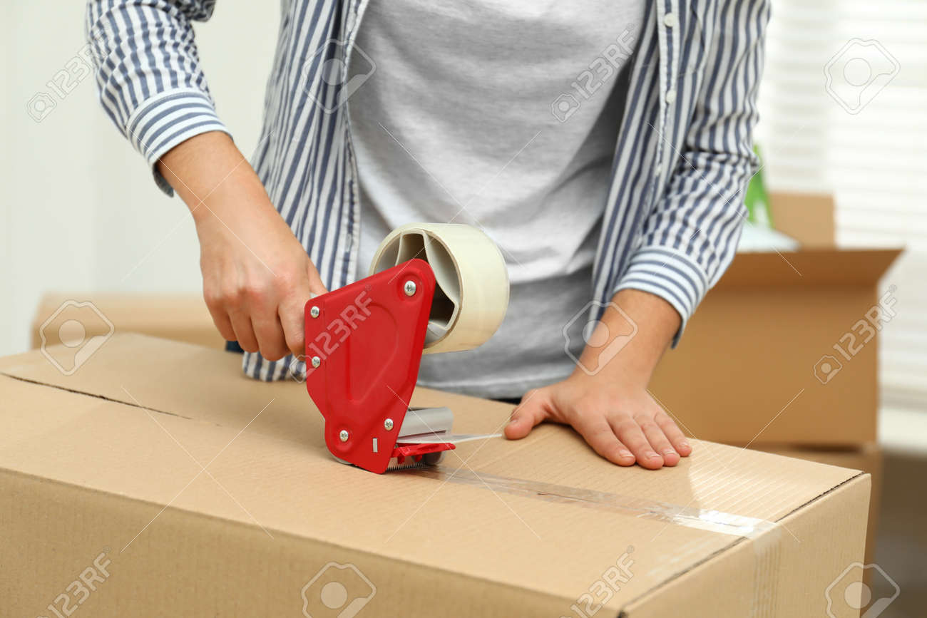 Woman packing cardboard box indoors, closeup. Moving day - 134622464 Woman packing cardboard box indoors, closeup. Moving day - 134622464