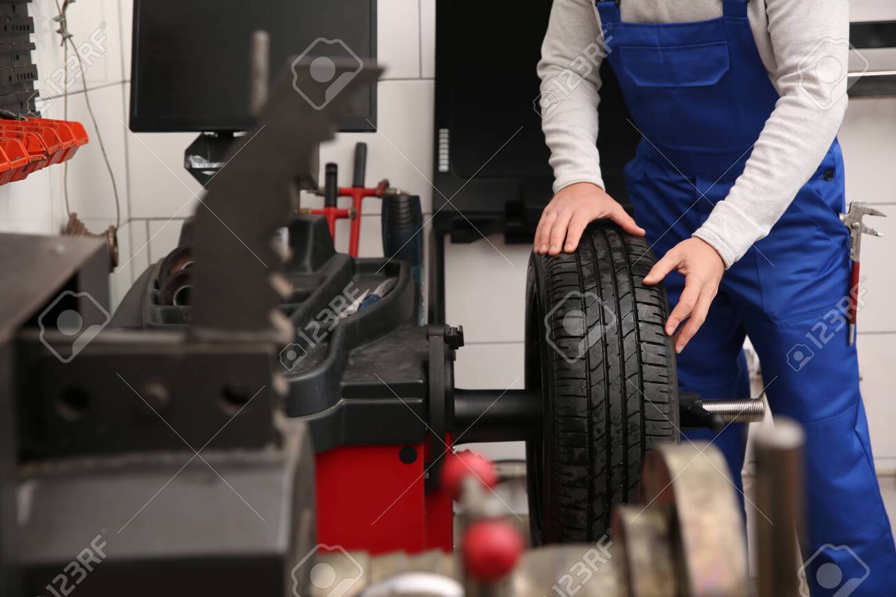 Mechanic working with wheel balancing machine at tire service, closeup - 143487821 Mechanic working with wheel balancing machine at tire service, closeup - 143487821