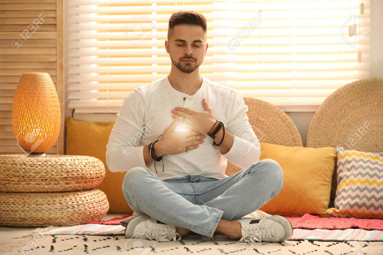 Young man during self-healing session in therapy room - 144632391 Young man during self-healing session in therapy room - 144632391