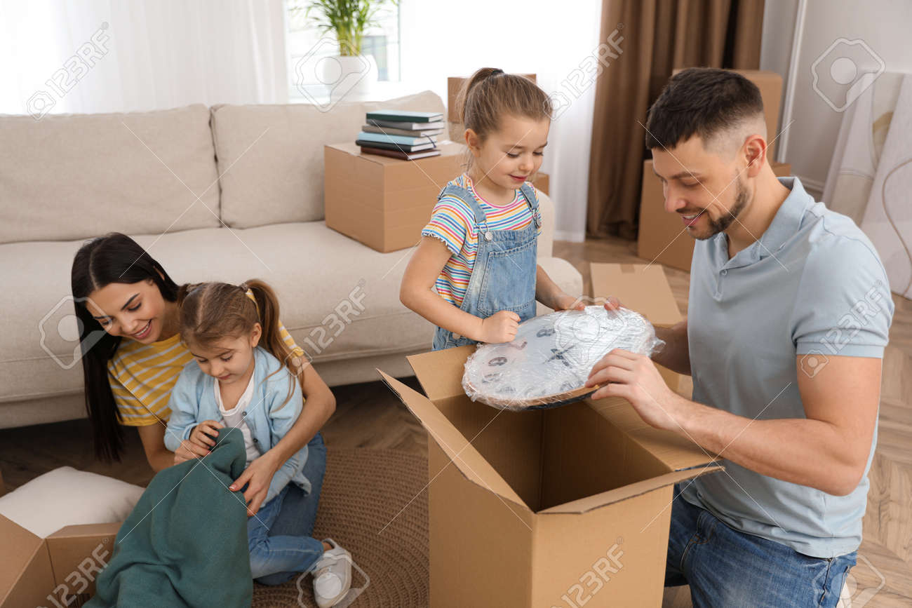 Happy family unpacking moving boxes at their new house - 166677698 Happy family unpacking moving boxes at their new house - 166677698