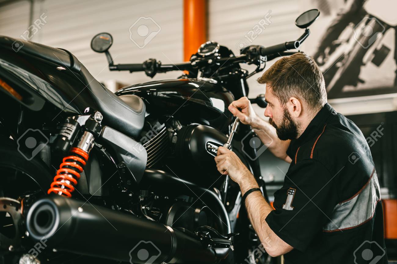 Mecánico Profesional De Trabajo De Destornilladores Y Reparaciones De Motos.  Hombre Joven Hermoso Que Repara La Motocicleta En El Taller De  Reparaciones. Fotos, Retratos, Imágenes Y Fotografía De Archivo Libres De  Derecho.