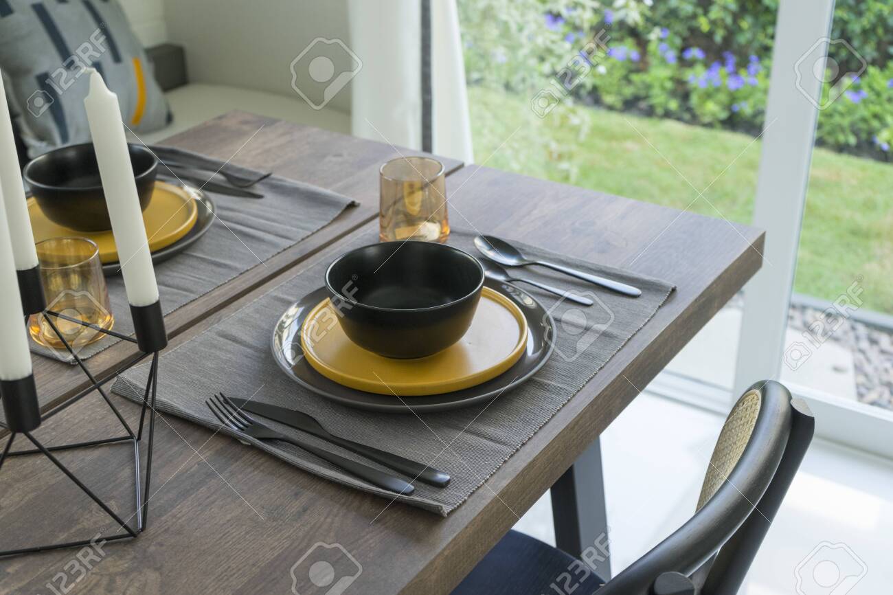 Dining Table With Black And Yellow Plate Setting In Modern Home