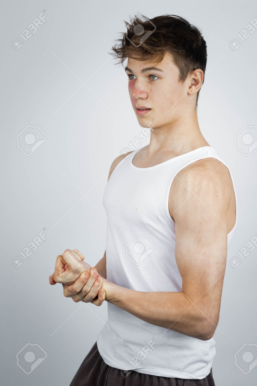 白いタンクトップを着て腕の筋肉を曲げる17歳の10代の少年の写真素材  