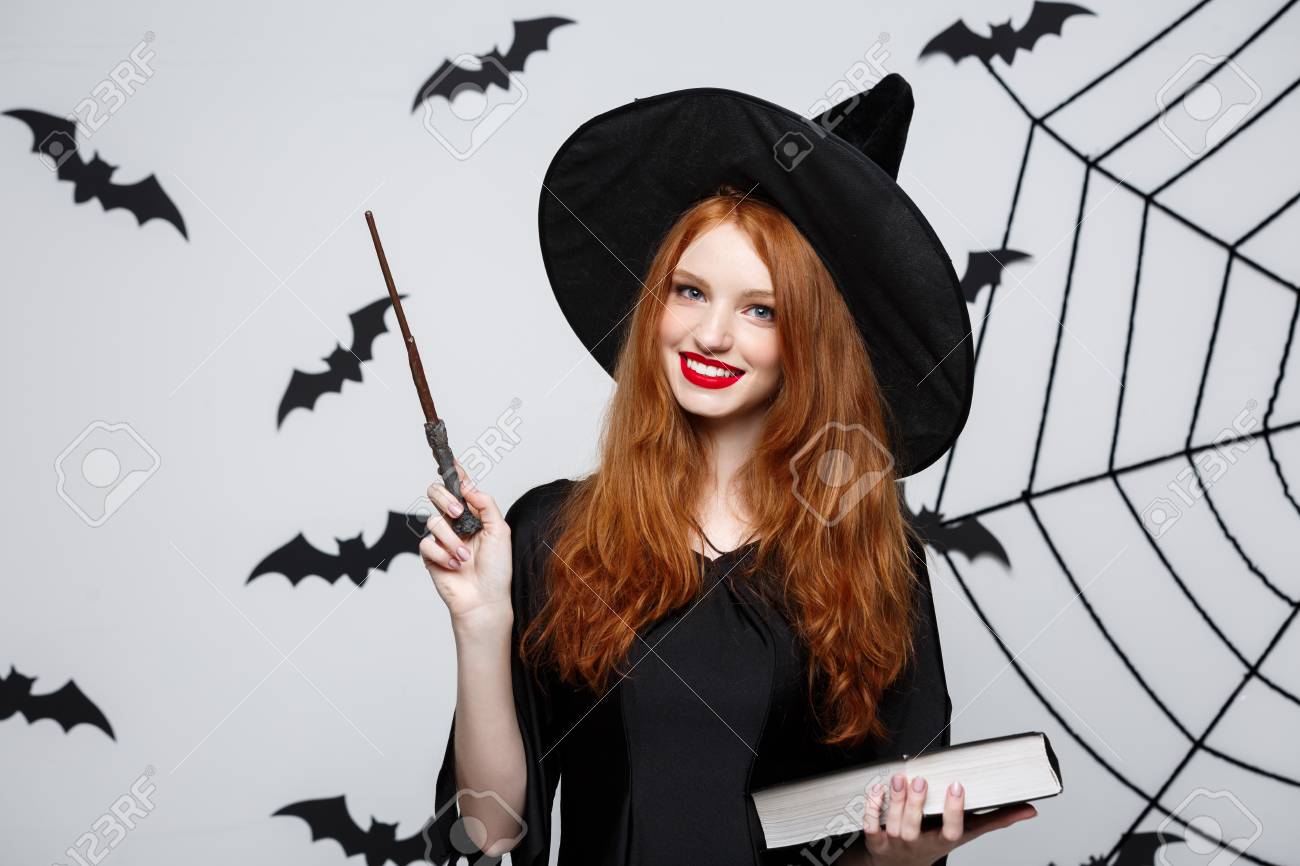 Halloween Concept - Beautiful Witch playing with magic stick on grey background. - 97604922 Halloween Concept - Beautiful Witch playing with magic stick on grey background. - 97604922