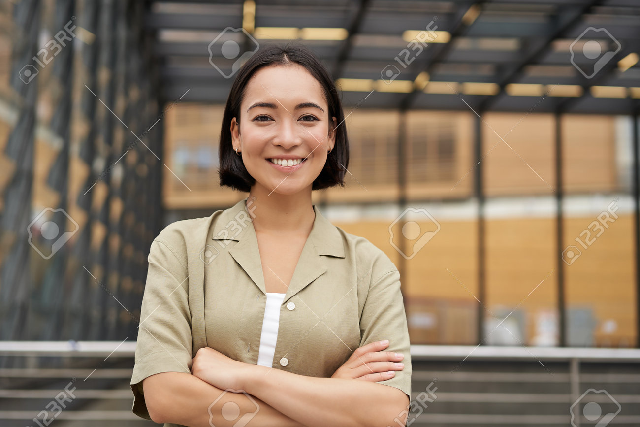 ポートレート 学生 人。自信に満ちた韓国の女の子のポートレート、若い学生の胸に腕を組む、パワーポーズで立ち、カメラに微笑むの写真素材・画像素材 Image 195360676