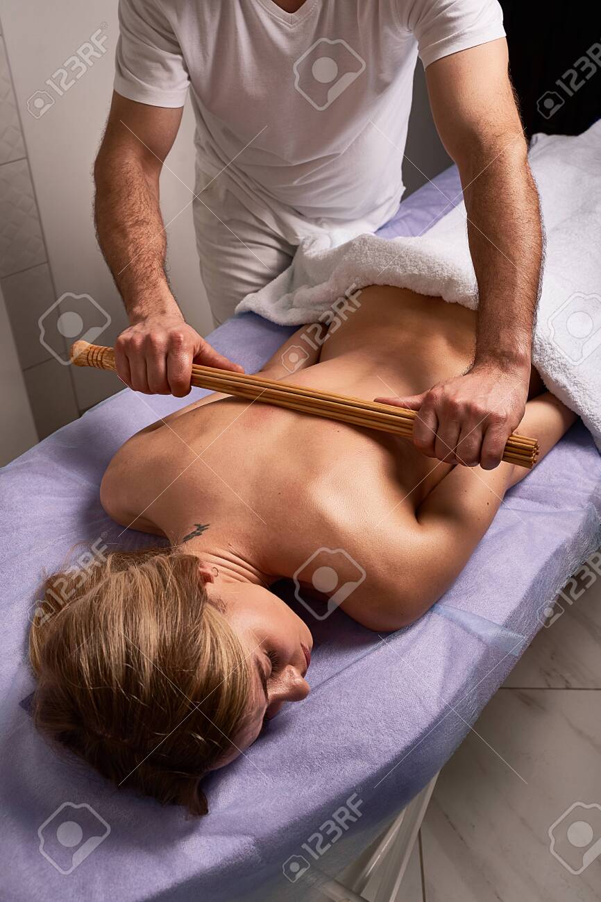 Male Masseur Doing Japanese Massage With Bamboo Sticks On Beautiful Naked  Woman Body In The Spa Salon. Beauty Treatment Concept. Stock Photo, Picture  and Royalty Free Image. Image 143476910.