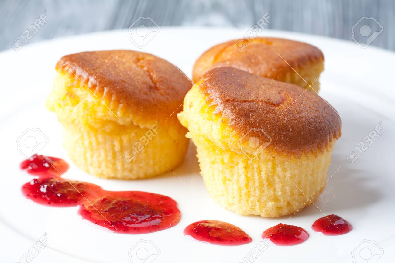 Delicious muffins on a white plate. With a red berry sauce. Gray background. (soft focus) - 35775711 Delicious muffins on a white plate. With a red berry sauce. Gray background. (soft focus) - 35775711