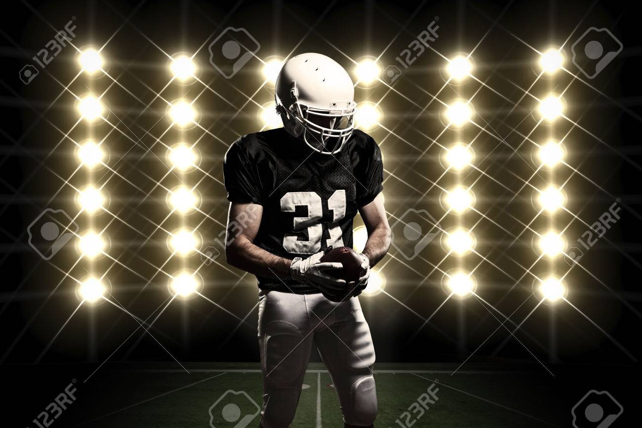 Football Player with a black uniform celebrating in front of lights. - 24750236 Football Player with a black uniform celebrating in front of lights. - 24750236