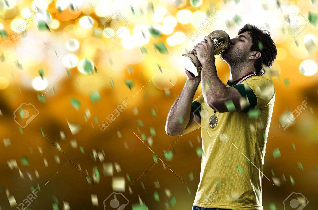 Brazilian soccer player, celebrating the championship with a trophy in his hand, on a yellow background. - 28208627 Brazilian soccer player, celebrating the championship with a trophy in his hand, on a yellow background. - 28208627