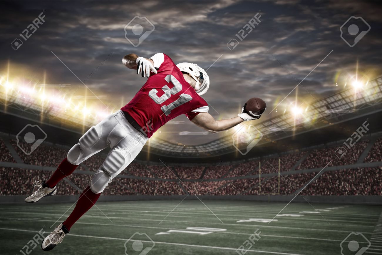 Football Player with a red uniform catching a ball on a stadium. - 50884852 Football Player with a red uniform catching a ball on a stadium. - 50884852
